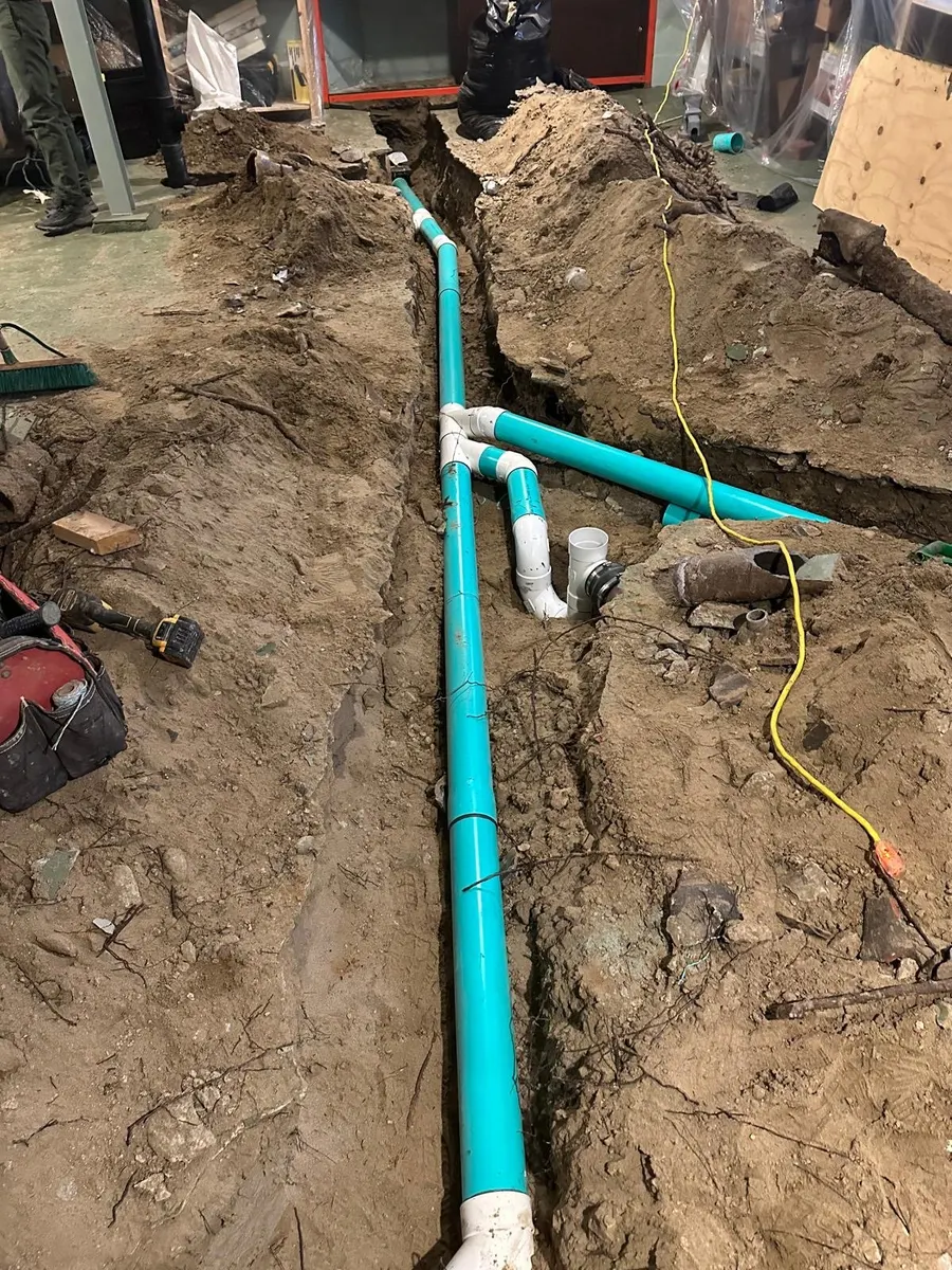 New PVC drain line laid in a basement floor trench